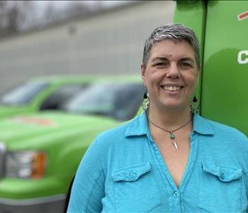 Female SERVPRO of Charlottesville employee standing in front of our green vehicles.
