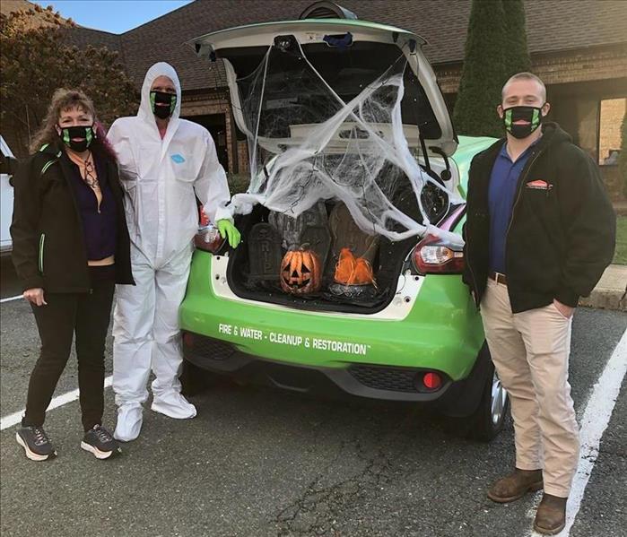 Three SERVPRO of Charlottesville employees next to the trunk of our Juke, decorated for Halloween.