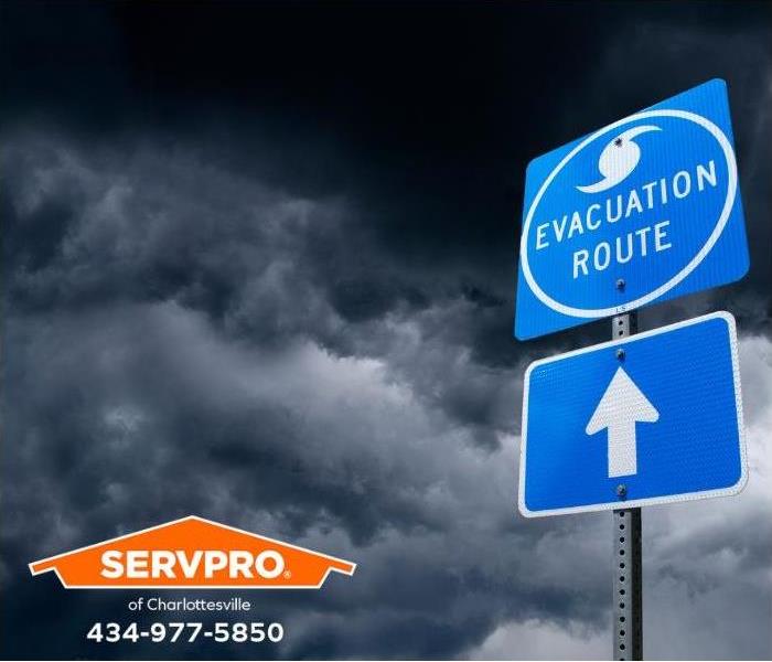 An “evacuation route” sign is shown amidst dark storm clouds.