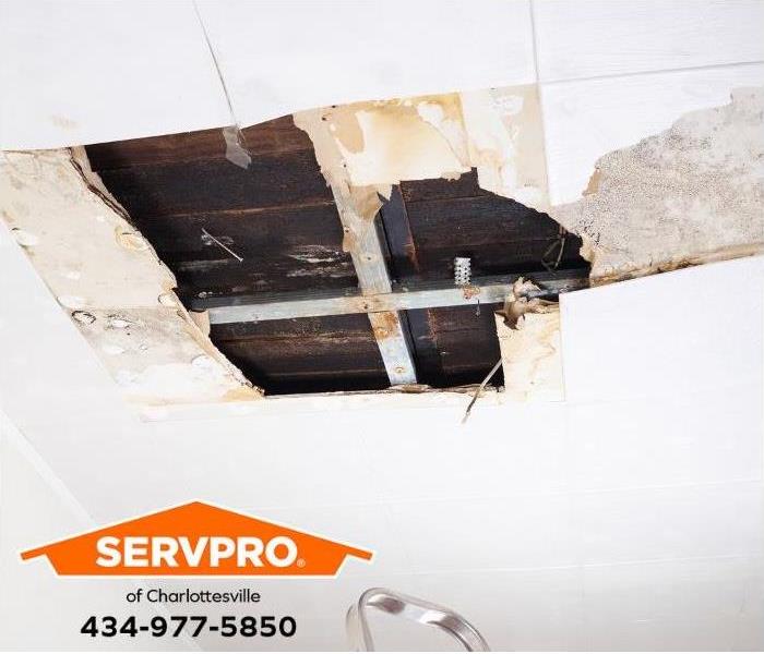 A water-damaged ceiling exposes floorboards from the floor above.