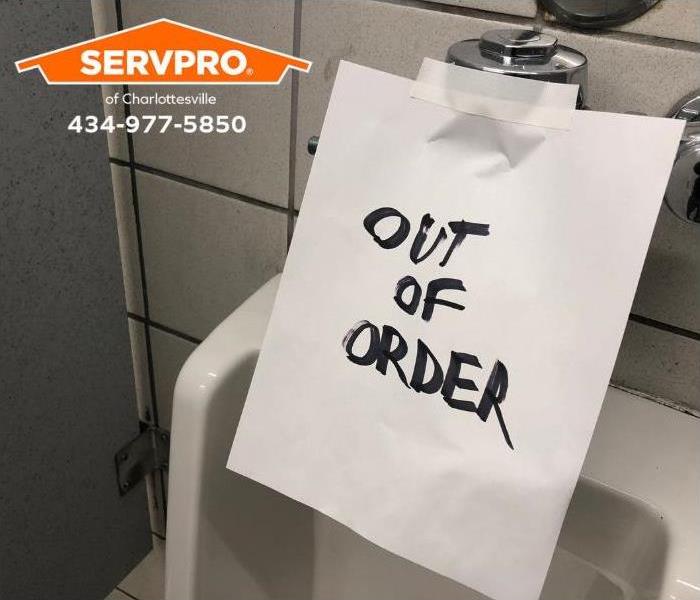An "out of order" sign is taped inside a public restroom. 