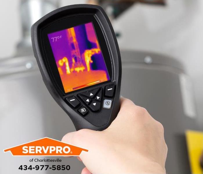 A technician uses thermal imaging to inspect a hot water pipe. 