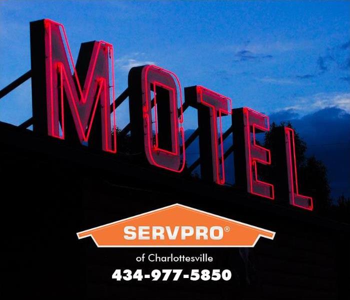 A large neon sign flashes the word, “Motel” in red light above a motel. 